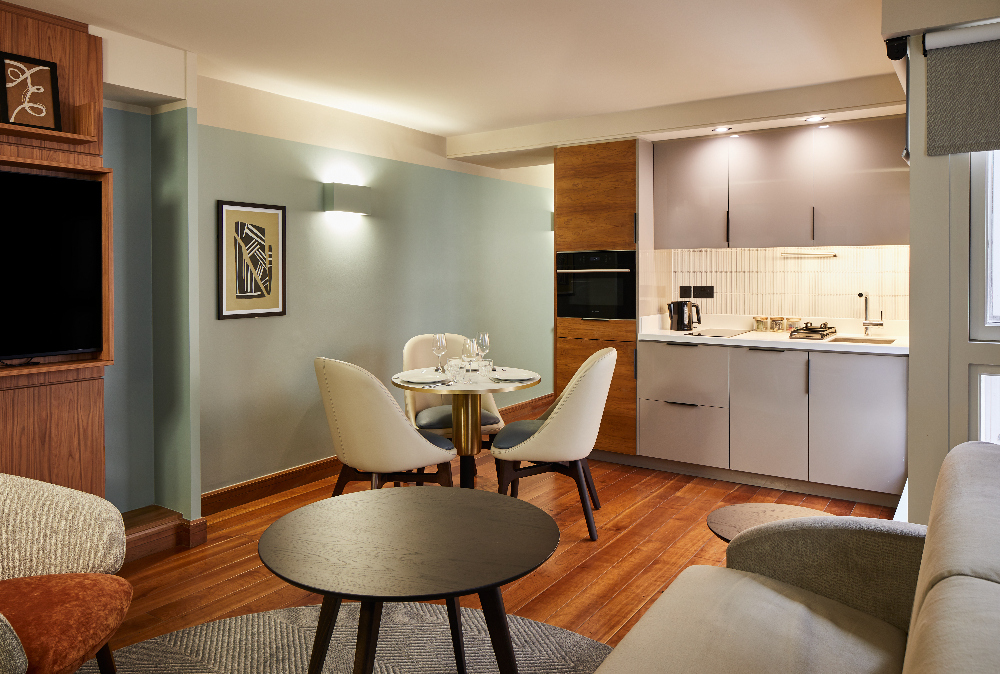 Modern open plan living and kitchen area at master Farringdon London serviced apartments, featuring a seating space, round dining table, and fully-equipped kitchen.