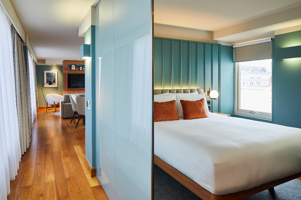 Contemporary bedroom space at master Farringdon London serviced apartments, separated by a glass wall, with a stylish bed, soft lighting, and city views through the window.