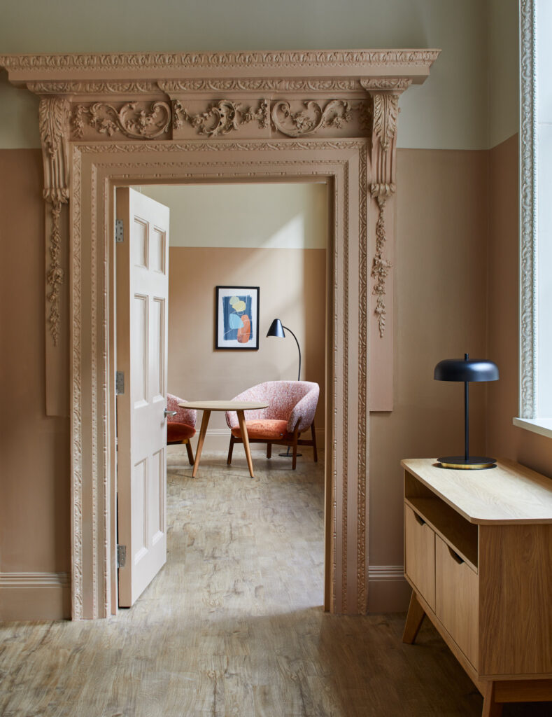 Interior view through an ornate, carved doorway at master Cannon London apartments, showcasing refined furnishings and soft, modern lighting.