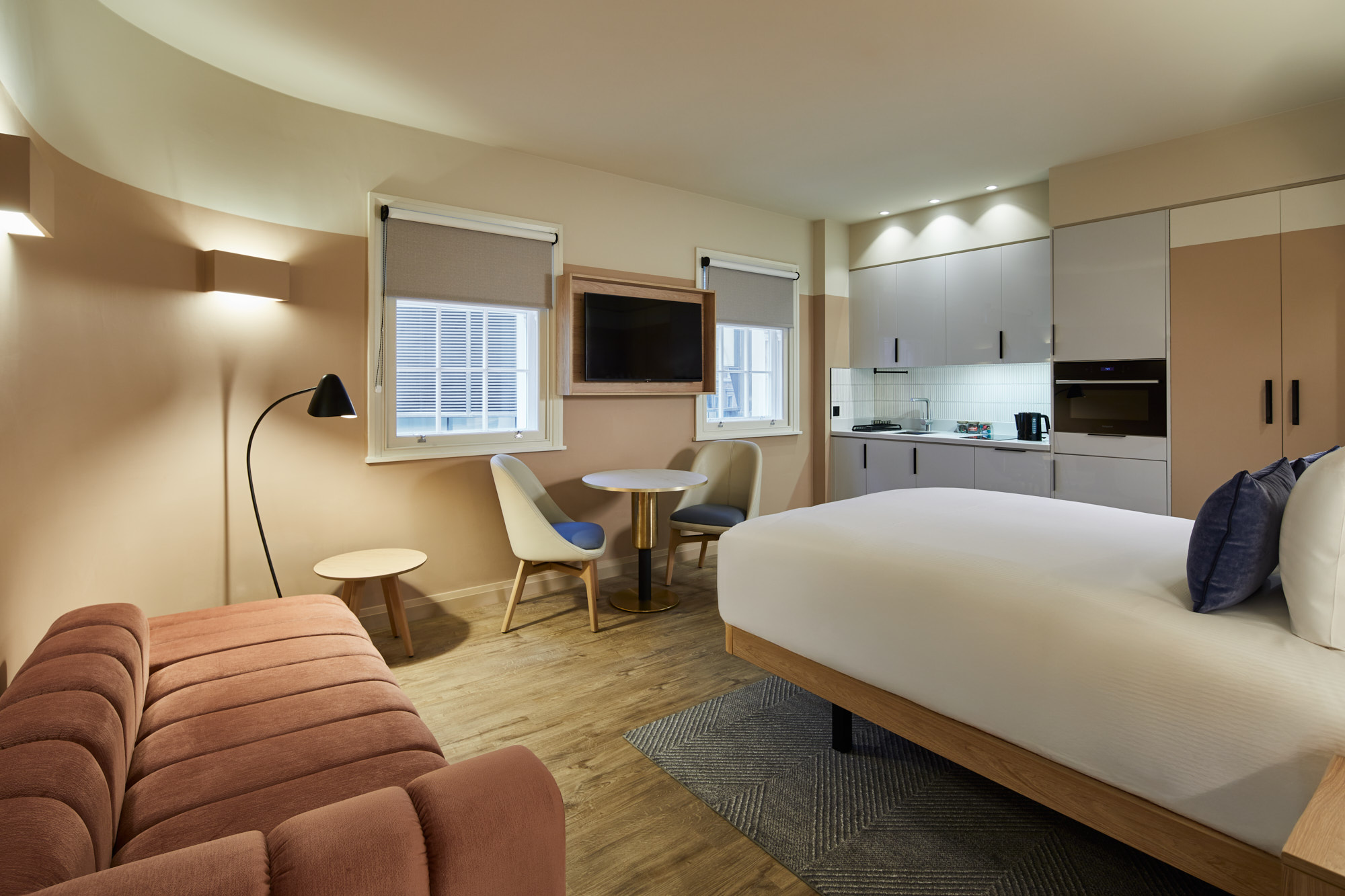 Open-plan studio with sofa bed at master Cannon London featuring sleeping and living areas, kitchen, and a cozy round dining table.