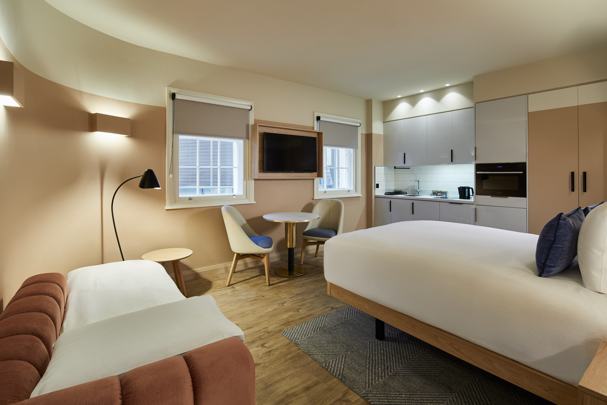 Open-plan studio with sofa bed at master Cannon London featuring sleeping and living areas, kitchen, and a cozy round dining table.