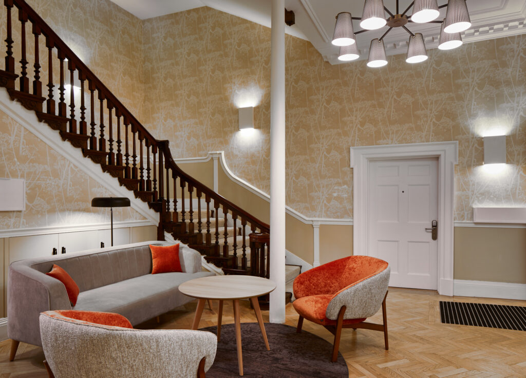 Sophisticated lobby area at master Cannon London apartments with stylish seating, contemporary decor, and a wooden staircase leading upstairs.