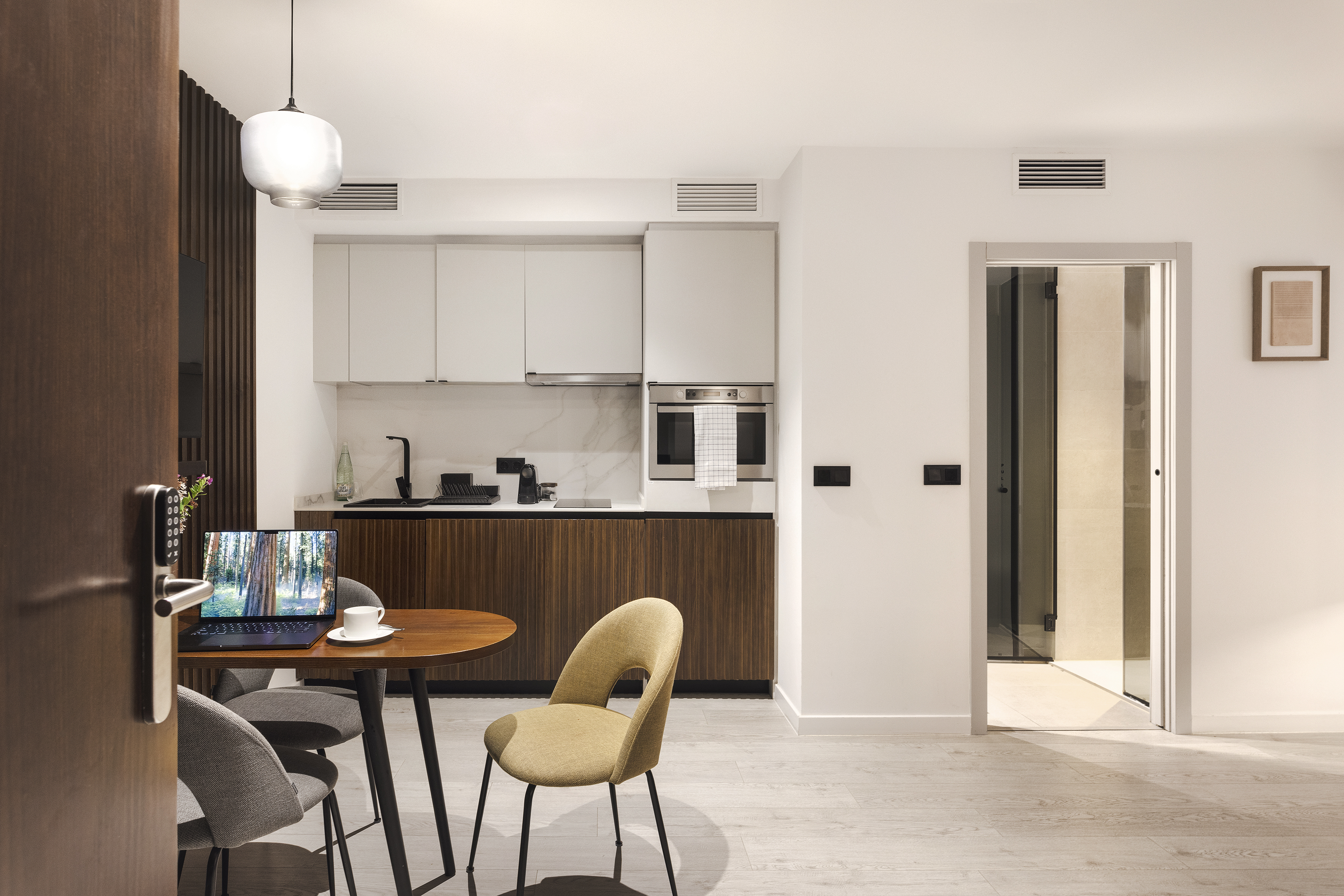 Interior One Bedroom Apartment at master La Rambla Barcelona featuring modern kitchen, dining table, and laptop workspace.