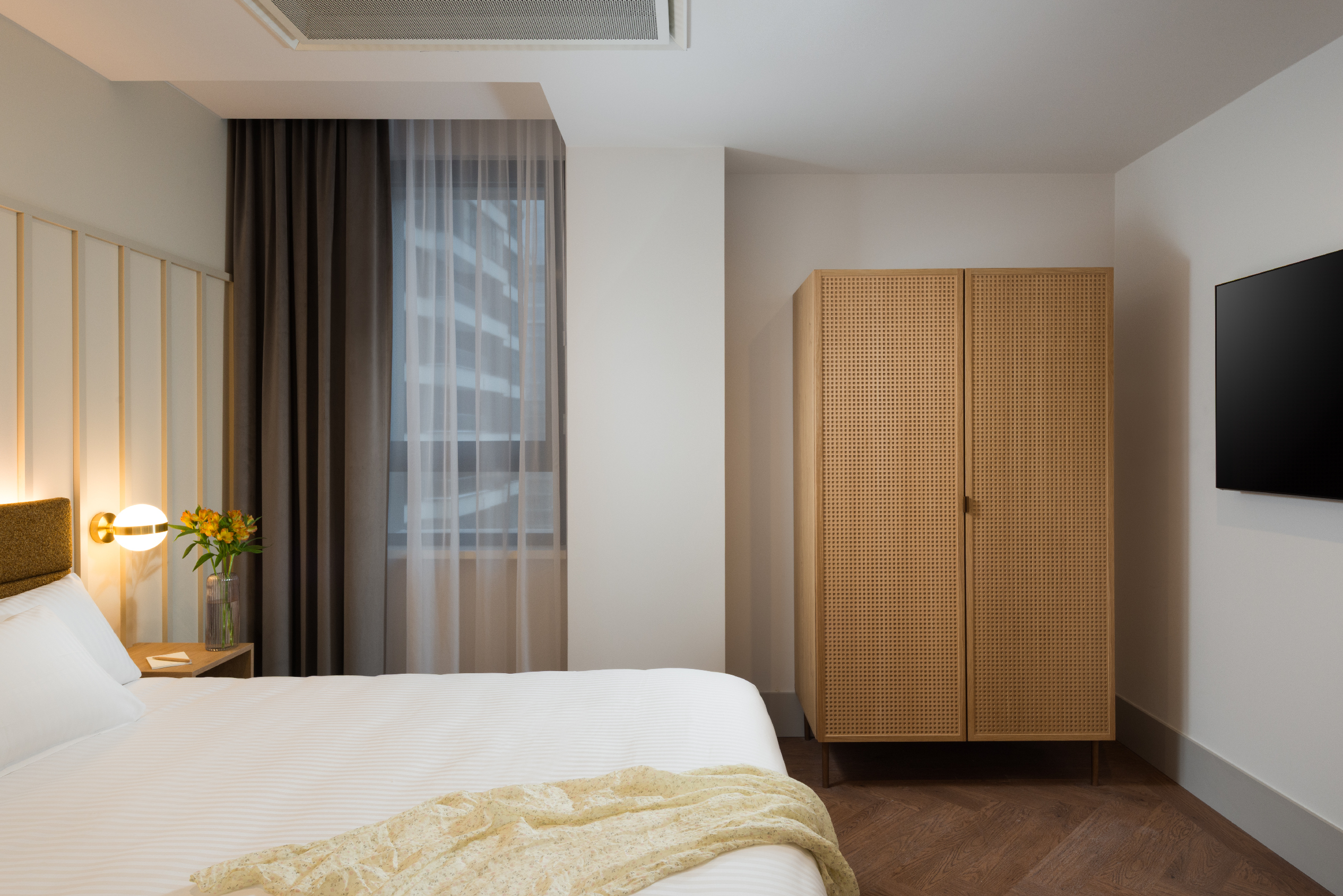 One-bedroom apartment bedroom at master Wola Serviced Apartments with double bed, wardrobe, and soft natural lighting