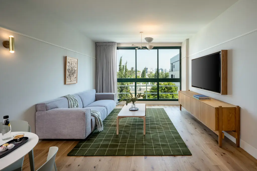 Spacious and modern living area in the One-Bedroom at master Mazeh Tel Aviv, featuring a cozy sofa and stylish decor.