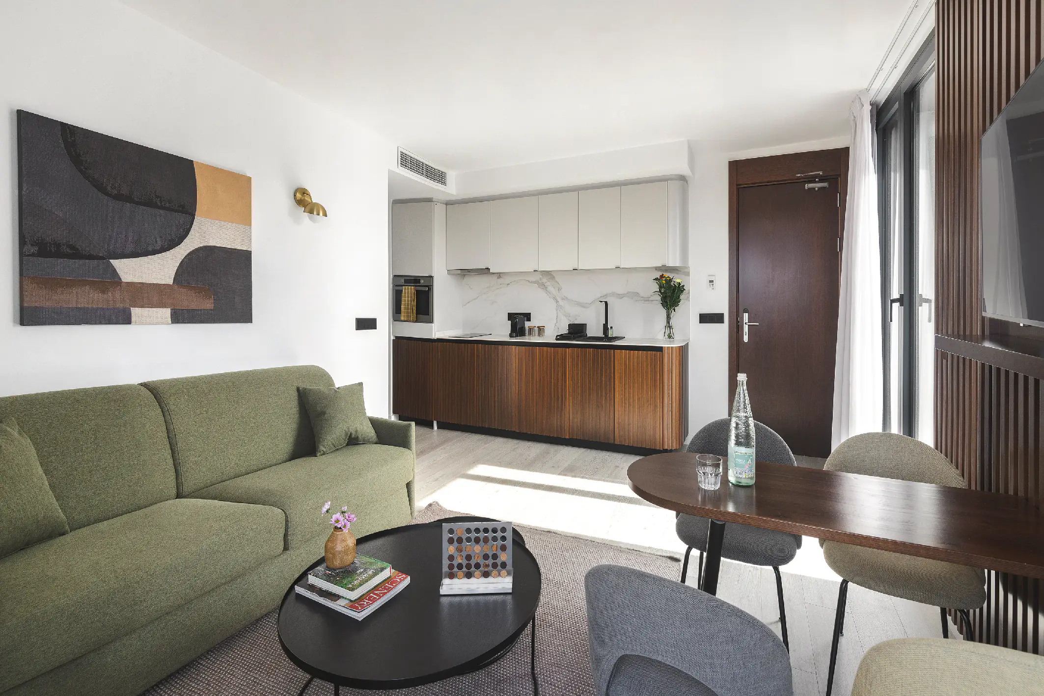 Contemporary penthouse living room with green sofa, wood accents, and full kitchen, opening onto a private terrace.